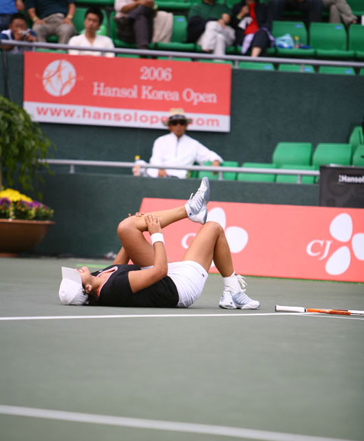 Eleni Daniilidou who is seized by a cramp on her left leg, falls on the floor after she beat Japan's Ai Sugiyama at the final match of the Hansol Korea Open Tennis Championships in Seoul October 1, 2006